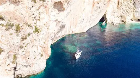 Veduta dall’alto dell’isola di Atokos, con la barca ferma sotto una parete rocciosa che scende a picco nel mare turchese, durante una sosta fotografica lungo la costa.